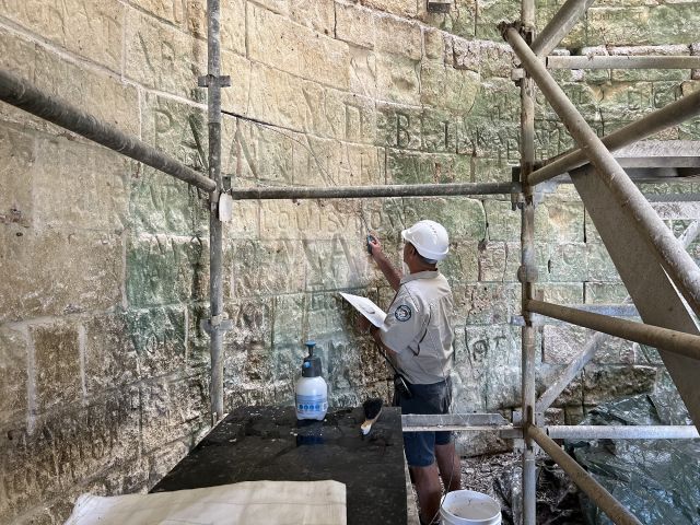 Photo of a man restoring the inside of the Raine Island beacon which has around 900 legible carved or painted inscriptions inside.