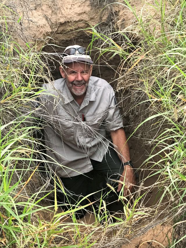 Photo of Alan Horsup standing in a large wombat burrow at Epping Forest National Park (Scientific).